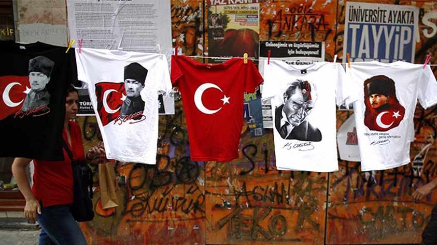 People walk by T-shirts with portraits of Mustafa Kemal Ataturk, founder of modern Turkey, displayed for sale near Taksim Square in Istanbul June 8, 2013. Thousands of Turks dug in on Saturday for a weekend of anti-government demonstrations despite Prime Minister Tayyip Erdogan's demand for an immediate end to protests that have spawned the most violent riots of his decade in power. REUTERS/Stoyan Nenov (TURKEY - Tags: POLITICS CIVIL UNREST TPX IMAGES OF THE DAY) - RTX10G76