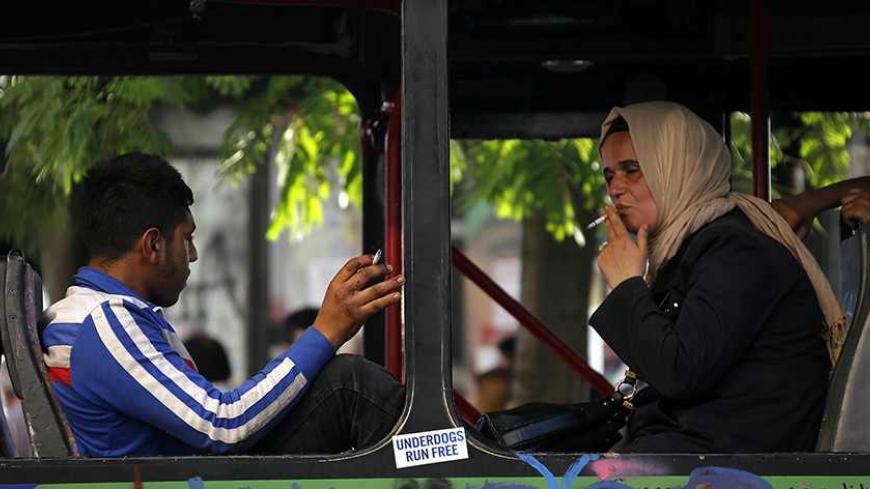 A woman wearing a traditional head-scarf smokes a cigarette inside a damaged bus used by anti-government protesters as a barricade in Istanbul's Taksim square June 10, 2013. REUTERS/Yannis Behrakis (TURKEY - Tags: CIVIL UNREST POLITICS) - RTX10IVP