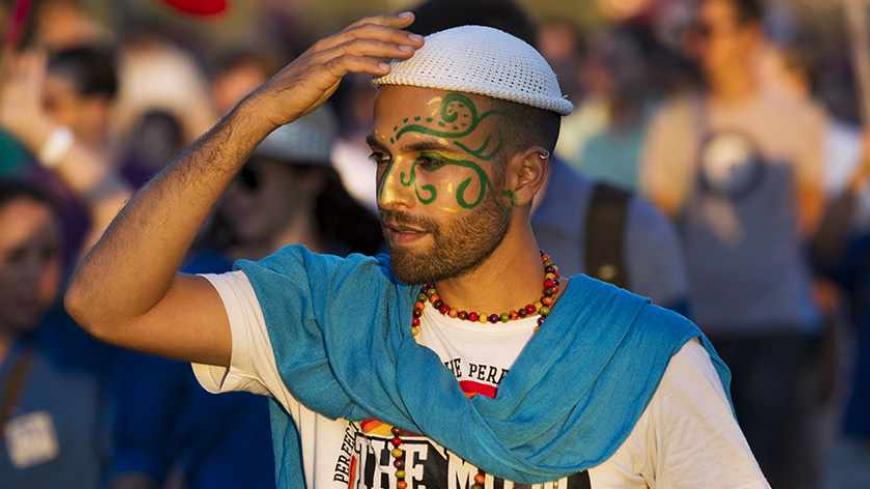 A participant touches his kippah, or skullcap, during the 12th annual gay pride parade in Jerusalem August 1, 2013. Some 2500 people on Thursday took part in the annual parade in Jerusalem. REUTERS/Ronen Zvulun (JERUSALEM - Tags: SOCIETY) - RTX127G7