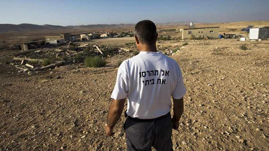 A Bedouin man, wearing a T-shirt reading which reads: "Don't destroy my home", stands in the village of Alsra, one of the dozens of ramshackle Bedouin Arab communities in the Negev desert which are not recognised by the Israeli state, in southern Israel August 18, 2013. For decades Arab Bedouins have eked out a meagre existence in the Negev desert, largely under the Israeli government's radar, but now many will have to make way for new developments. Israel has already invested around $5.6 billion to build m