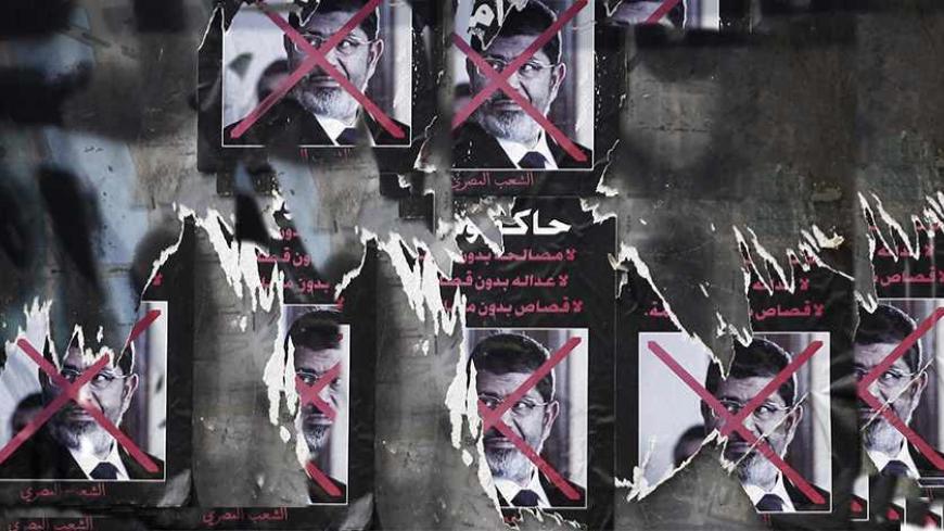Torn posters of ousted Egyptian President Mohamed Mursi are seen on a wall at Tahrir Square in Cairo September 26, 2013. On Thursday, the groundwork for the construction of a garden was begun at the square. The poster reads, "To be on trial... No reconciliation without justice, no justice without retribution, no punishment without trial". REUTERS/Amr Abdallah Dalsh  (EGYPT - Tags: POLITICS CIVIL UNREST) - RTX140EG