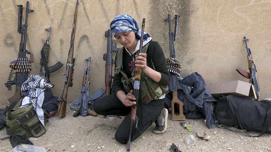A Kurdish female fighter from Kurdish People's Protection Units (YPG) checks her weapon near Ras al-Ain, in the province of Hasakah, after capturing it from Islamist rebels November 6, 2013. Redur Xelil, spokesman for the armed wing of the Syrian Kurdish Democratic Union Party (PYD), said Kurdish militias had seized the city of Ras al-Ain and all its surrounding villages. Syrian Kurdish fighters have captured more territory from Islamist rebels in northeastern Syria, a Kurdish militant group said on Monday,