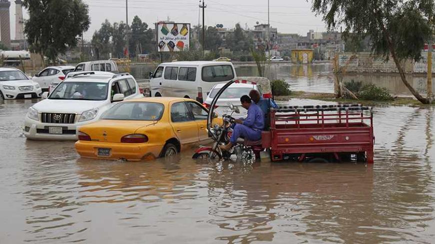 Vehicles are seen along a flooded street after heavy overnight rains in Baghdad, November 11, 2013. Baghdad's streets were knee deep in dirty water after heavy overnight rains. Residents struggle with the poor sewage system and lack of municipal services. REUTERS/Ahmed Saad  (IRAQ - Tags: ENVIRONMENT SOCIETY) ) - RTX1597K