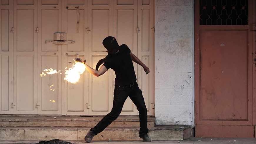 A masked Palestinian protester throws a Molotov cocktail during clashes with Israeli security officers following the funerals of three Palestinians, in West Bank city of Hebron November 27, 2013. Israeli security officials said their forces killed three Palestinian militants on Tuesday who were part of an al Qaeda-linked network in the West Bank. REUTERS/Ammar Awad (WEST BANK - Tags: POLITICS CIVIL UNREST TPX IMAGES OF THE DAY) - RTX15V3A