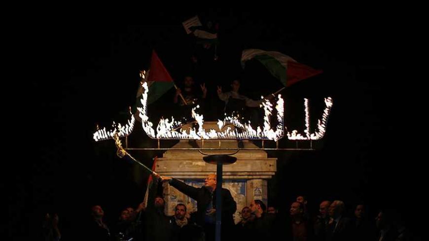 A Palestinian uses a torch to light a sign that reads "no to the blockade" during a protest against the blockade on Gaza in Gaza City November 30, 2013. Israel imposed a blockade on Gaza in 2007 after Islamist group Hamas seized control of the territory in a brief civil war with Western-backed Palestinian President Mahmoud Abbas's Fatah party. REUTERS/Suhaib Salem (GAZA - Tags: CIVIL UNREST POLITICS) - RTX15YUD