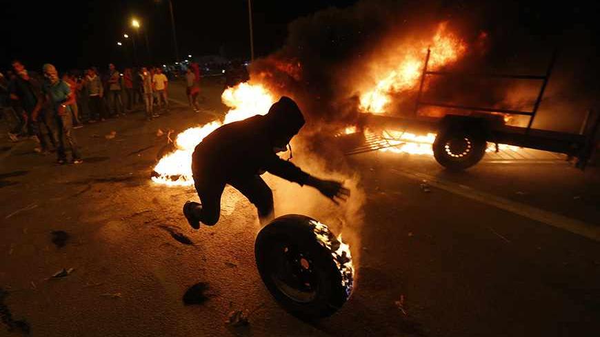A protester rolls a burning tyre towards Israeli police during a demonstration showing solidarity with Bedouin Arabs who are against a government displacement plan for Bedouins in the Southern Negev desert in the village of Hura in southern Israel November 30, 2013. REUTERS/Baz Ratner  (ISRAEL - Tags: CIVIL UNREST POLITICS TPX IMAGES OF THE DAY) - RTX15YV8
