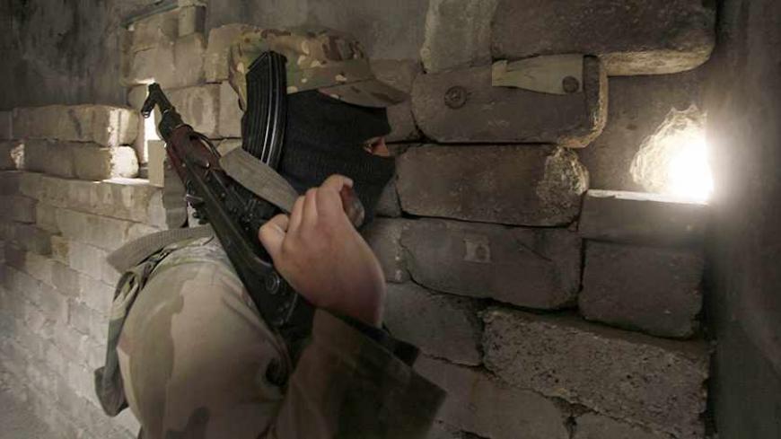 A member of the Islamic State of Iraq and the Levant carries his weapon as he looks through a hole in a wall in Sheikh Saeed neighbourhood December 4, 2013. REUTERS/Molhem Barakat (SYRIA - Tags: POLITICS CIVIL UNREST CONFLICT MILITARY) - RTX163J6