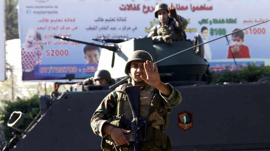 A Lebanese army soldier gestures as they are deployed on their military vehicles on the streets of Sidon, southern Lebanon December 16, 2013. Gunmen attacked two army checkpoints outside the southern Lebanese city of Sidon on Sunday, killing a soldier and wounding three others, the army said. Four attackers were also killed in the clashes around the Mediterranean city, which was the scene of heavy fighting six months ago between the army and supporters of a Sunni Muslim cleric who backs rebels in neighbouri