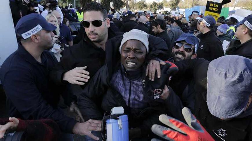 Israeli immigration policemen force an African migrant onto a bus headed to a prison, during a protest in front of the Knesset, the Israeli parliament, in Jerusalem December 17, 2013. Israeli police on Tuesday sent back to custody more than 150 African migrants who had abandoned a desert holding facility in protest of a new law allowing them to be kept there indefinitely. REUTERS/Ammar Awad (JERUSALEM - Tags: SOCIETY IMMIGRATION POLITICS CIVIL UNREST) - RTX16MBK