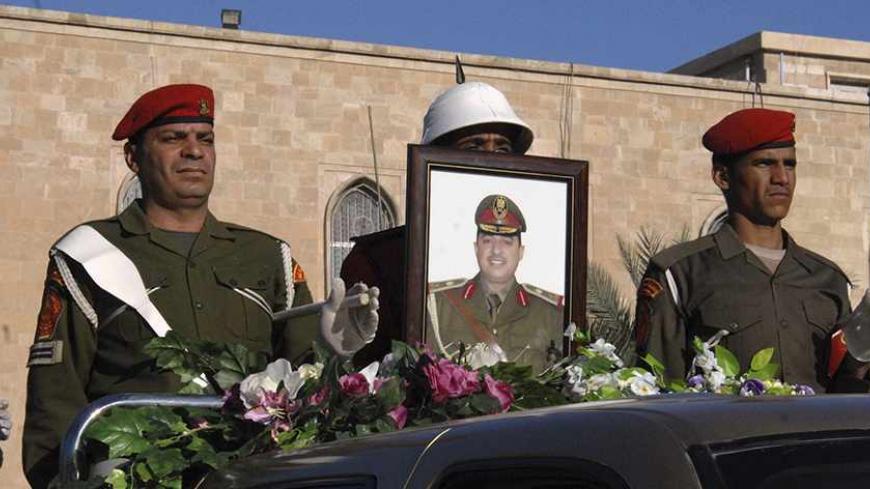 Soldiers on a back of military vehicle carrying the coffin of the Commander of the army's Seventh Division Maj. Gen Mohammed Ahmed al-Kurwi during a funeral ceremony in Baghdad December 22, 2013. Militants killed at least 18 Iraqi officers and soldiers in Sunni-dominated Anbar province on Saturday, including Kurwi, who oversaw a crackdown on Sunni protesters earlier this year, military sources said. REUTERS/stringer (IRAQ - Tags: CIVIL UNREST CONFLICT MILITARY) - RTX16RMM
