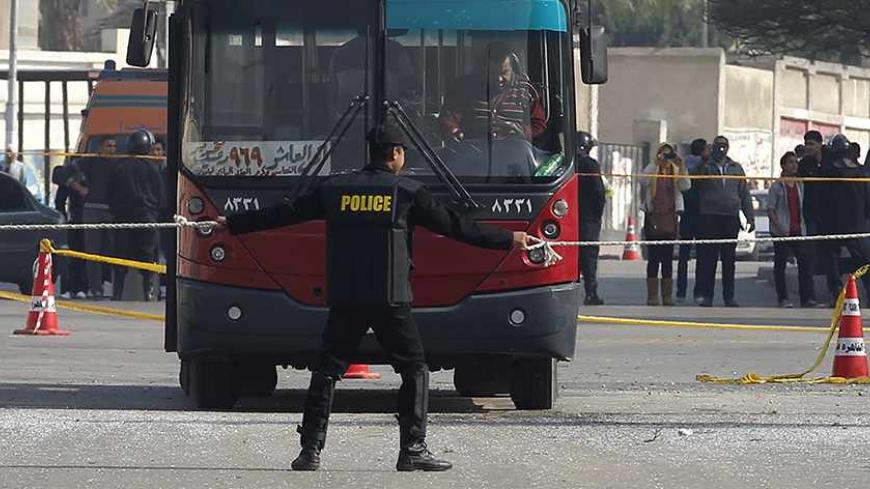 A policeman stands guard at the scene of a bomb blast that damaged a bus near the Al-Azhar University campus in Cairo's Nasr City district December 26, 2013. The bomb blast hit the bus on Thursday, injuring four people, a spokesman for Egypt's interior ministry told Reuters, two days after a car bomb killed 16 in the Nile Delta. REUTERS/Amr Abdallah Dalsh (EGYPT - Tags: POLITICS CIVIL UNREST) - RTX16U8W