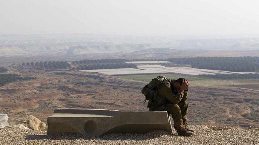 An Israeli soldier rests after completing a 45 km march near the Jewish settlement of Tomer in the Jordan Valley January 2, 2014. Control of the Jordan Valley is one of a number of contentious issues on which Israelis and Palestinians are in dispute in current peace talks. U.S. Secretary of State John Kerry arrived in Israel on Thursday to help re-energise peace negotiations. REUTERS/Ronen Zvulun (WEST BANK - Tags: POLITICS MILITARY TPX IMAGES OF THE DAY) - RTX16ZUQ