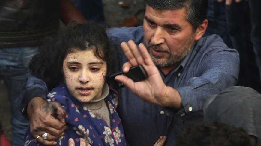 A man gestures as he holds a wounded girl at the site of an explosion in Beirut's southern suburbs, January 2, 2014. A car bomb killed four people in Hezbollah's southern Beirut stronghold on Thursday, security and medical sources said, the latest in a series of deadly attacks on Shi'ite and Sunni targets in Lebanon.  REUTERS/Issam Kobeisi (LEBANON - Tags: POLITICS CIVIL UNREST) - RTX17039