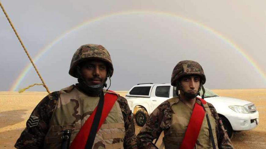 Jordanian soldiers look on as a rainbow is seen the background, before the arrival of Syrian refugees who are fleeing the violence in their country, near the town of Ruwaished, 240 km (149 miles) east of Amman December 5, 2013. REUTERS/Muhammad Hamed (JORDAN - Tags: POLITICS MILITARY CIVIL UNREST) - RTX165HC