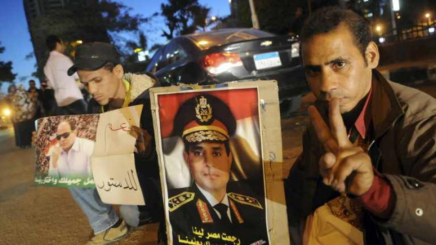 Egyptians hold pictures of Egypt's Army Chief General Abdel Fattah al-Sisi during a protest against what they say is Qatar's backing of ousted Egyptian president Mohamed Mursi's government, outside the Qatari Embassy in Cairo, December 6, 2013.  REUTERS/Stringer (EGYPT  - Tags: POLITICS CIVIL UNREST) - RTX167E8