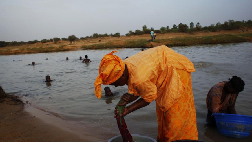People bathe and wash clothes in the Senegal river outside the town of Kaedi, Gorgol region, in Mauritania June 1, 2012. A full third of the country's population, amounting to around a million people, are at risk of malnutrition if rain doesn't fall by July, according to estimates from Spanish Non-Governmental Organization Accion contra el Hambre (Action Against Hunger), which has been warning about food crisis since the beginning of the year after poor rains in 2011. REUTERS/Susana Vera (MAURITANIA - Tags: