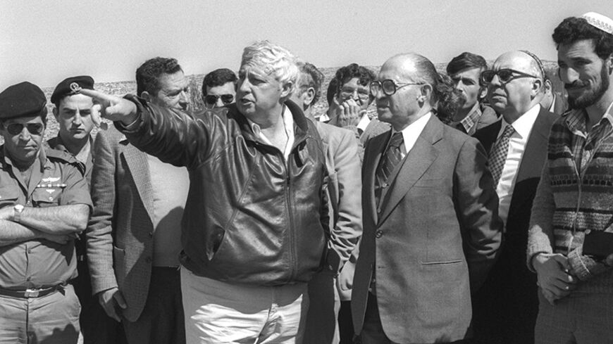 Israeli Prime Minister Menahem Begin (3rd R) listens to Israeli Agriculture Minister Ariel Sharon (C) during a visit to the West Bank settlement of Alon Moreh February 27, 1981 in this handout photo released by the Government Press Office. Israeli Prime Minister Ariel Sharon, a dominant figure for decades in shaping the Middle East, suffered a massive brain haemorrhage on January 4, 2006, and doctors battled to save his life. ISRAEL OUT REUTERS/ Herman Chanania/Government Press Office/Handout - RTR17SBE