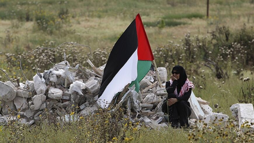 An Israeli Arab woman sits holding a Palestinian flag during a protest to mark the right of return for refugees who fled their homes during the 1948 war that followed the creation of Israel, which celebrated its 62nd anniversary near the Israeli Arab village of Tira April 20, 2010.  REUTERS/Ammar Awad (ISRAEL - Tags: POLITICS CIVIL UNREST) - RTR2D20I