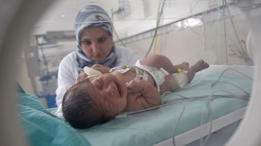 A Palestinian nurse tends to a baby inside an incubator in a hospital in Khan Younis in the southern Gaza Strip March 24, 2012. Israel allowed nine fuel tankers to cross into the Gaza Strip on Friday to ease a severe power shortage triggered by a dispute over supplies between Egypt and the enclave's Hamas Islamist rulers. The fuel crisis has crippled Gaza in recent weeks. Petrol pumps have run dry and its 1.7 million residents are suffering major electricity blackouts.  REUTERS/ Ibraheem Abu Mustafa (GAZA -