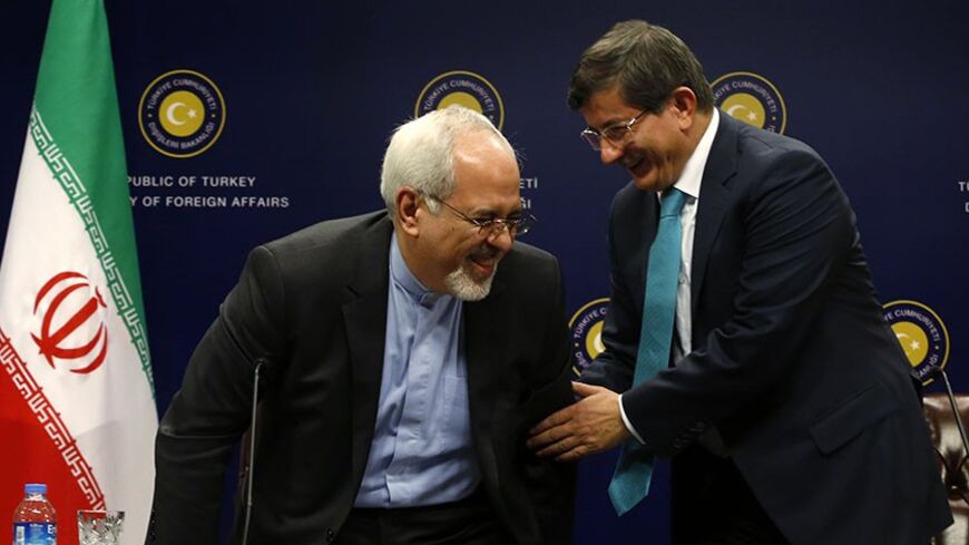 Turkish Foreign Minister Ahmet Davutoglu (R) helps Iranian Foreign Minister Mohammad Javad Zarif to stand during a news conference in Ankara November 1, 2013. Turkey and Iran said on Friday they had common concerns about the increasingly sectarian nature of Syria's civil war, signalling a thaw in a key Middle Eastern relationship strained by stark differences over the conflict. Davutoglu expressed his appreciation to Zarif at the start of the news conference for travelling to Turkey despite suffering from b