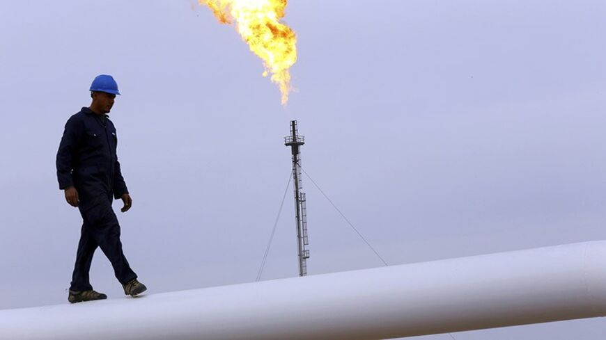 A worker walks on an oil pipeline at Khurmala oilfield on the outskirts of the city of Arbil, in Iraq's Kurdistan region December 4, 2013. REUTERS/Stringer (IRAQ - Tags: POLITICS ENERGY) - RTX163IY