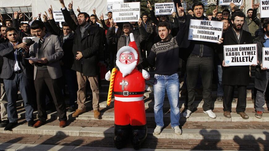 Turkish Islamist protesters shout slogans against Noel celebrations as they hold an inflatable Santa Claus toy during a demonstration at Beyazit Square in Istanbul December 26, 2013. The sign (front, 2nd) reads: "Christmas is a blow to our Islamism". REUTERS/Osman Orsal (TURKEY - Tags: RELIGION CIVIL UNREST) - RTX16UF4