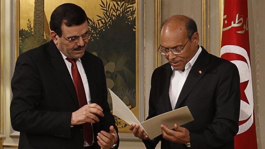 Tunisian President Moncef Marzouki (R) receives a letter of resignation from Prime Minister Ali Larayedh in Tunis January 9, 2014. Larayedh resigned on Thursday to make way for a caretaker administration as part of a deal with his opponents to finish a transition to democracy. REUTERS/Zoubeir Souissi (TUNISIA - Tags: POLITICS) - RTX177NG