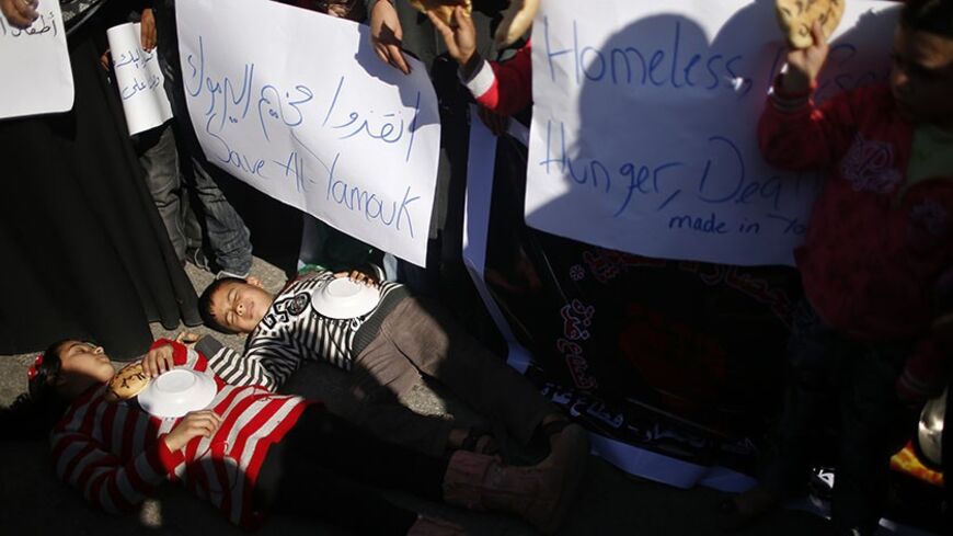 Palestinian children lie on the ground as they take part in a rally to show solidarity with Palestinian refugees in Syria's main refugee camp Yarmouk, in Gaza City January 16, 2014. REUTERS/Mohammed Salem (GAZA - Tags: POLITICS CIVIL UNREST) - RTX17G3R