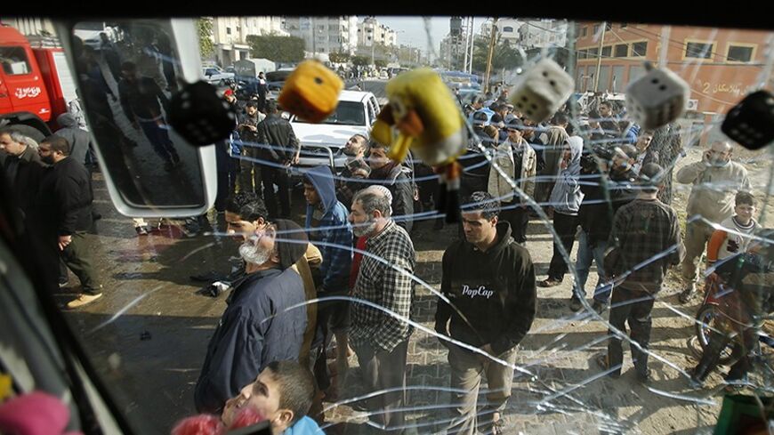 Palestinians are pictured through the damaged windscreen of a bus as they gather at the scene of an Israeli air strike, which hit a motorcycle, in the northern Gaza Strip January 19, 2014. Israel carried out an air strike on Sunday against a Gaza militant whom it blamed for cross-border rocket attacks last week. Palestinian medics said two people, including a 12-year-old boy, were wounded. REUTERS/Mohammed Salem (GAZA - Tags: POLITICS CIVIL UNREST TPX IMAGES OF THE DAY) - RTX17KW7
