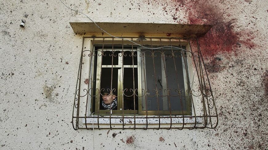A Palestinian man looks out a window beside bloodstains on the wall of a house at the scene of an Israeli air strike in Beit Hanoun, in the northern Gaza Strip January 22, 2014. Israel killed two Gaza gunmen in an air strike on Wednesday, blaming one of them for firing rockets across the border during former Israeli Prime Minister Ariel Sharon's funeral last week. Islamic Jihad claimed one man, Ahmed Al-Za'anin, as its own, without immediately commenting on the other's affiliation. REUTERS/Suhaib Salem (GAZ