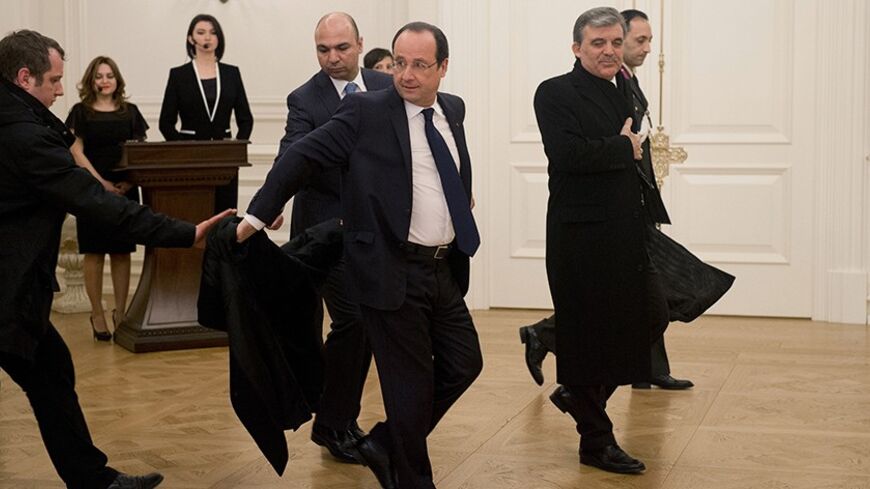 French President Francois Hollande (C) hands his overcoat to a body guard as he arrives with Turkey's President Abdullah Gul (R) to attend a state dinner, January 27, 2014, in Ankara, as part of Hollande's two-day state visit to Turkey. Picture taken January 27, 2014.   REUTERS/Alain Jocard/Pool   (TURKEY - Tags: POLITICS) - RTX17Y3E