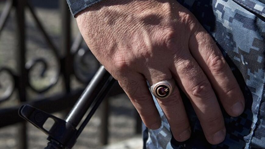 A policeman wears a ring showing the Islamic symbol of the star and crescent, as the barrel of a rifle is seen in the background, in the Chechen village of Itum-Kale April 29, 2013. The naming of two Chechens, Dzhokhar and Tamerlan Tsarnaev, as suspects in the Boston Marathon bombings has put Chechnya - the former site of a bloody separatist insurgency - back on the world's front pages. Chechnya appears almost miraculously reborn. The streets have been rebuilt. Walls riddled with bullet holes are long gone.