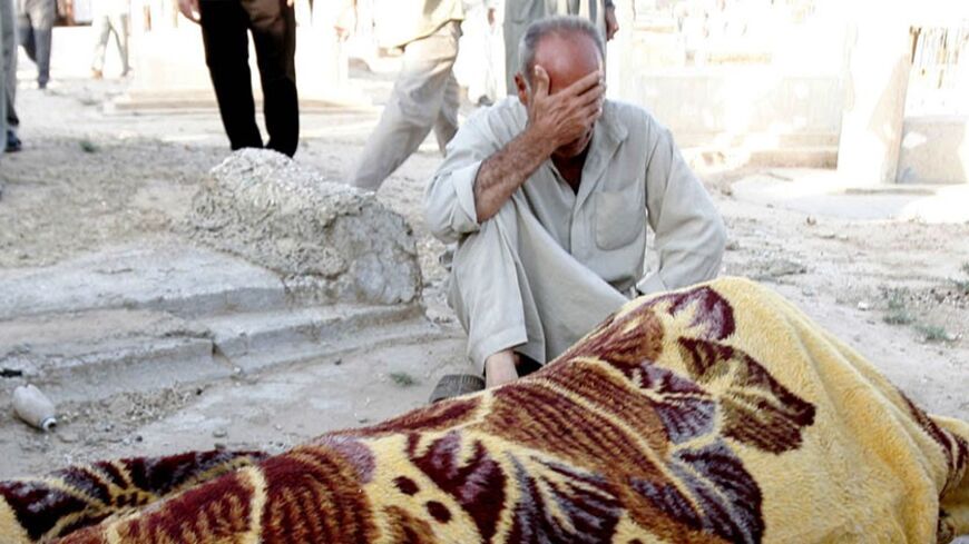 A man mourns near the body of his brother, wrapped in a blanket, who was among those killed during Sunday night's suicide bomb attack at a popular coffee shop in the town of Tuz Khurmatu, 170 km (106 miles) north of Baghdad, July 17, 2006. The attack killed 21 people, mostly elderly men. REUTERS/Slahaldeen Rasheed (IRAQ) - RTR1FKIO