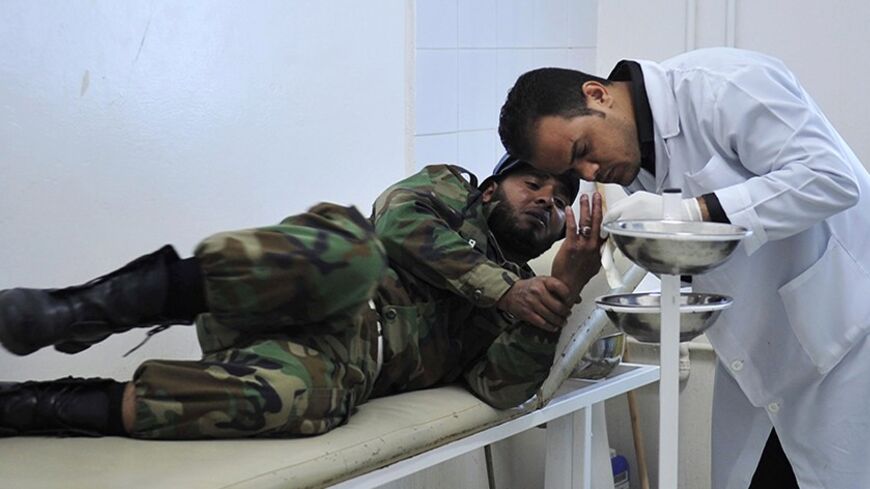 A medic treats a wounded rebel at a hospital in Ajdabiyah April 7, 2011. NATO said on Thursday it was looking into the details of an air strike on a column of tanks near the oil town of Brega, in which Libyan rebel fighters and a hospital nurse said five people had been killed. A Reuters reporter saw bloodstained stretchers being brought out of the hospital in Ajdabiyah, where those wounded in the air and rocket attacks were being treated.  REUTERS/Esam al-Fetori (LIBYA - Tags: POLITICS CIVIL UNREST IMAGES 