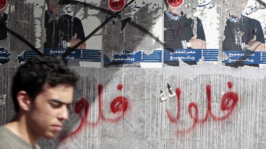 A man walks in front of defaced posters of presidential candidate and Egypt's former prime minister Ahmed Shafiq in Cairo April 29, 2012. Egypt's presidential election will be held on May 23 and 24.The graffiti reads "Feloul", meaning "Remnants". REUTERS/Amr Abdallah Dalsh  (EGYPT - Tags: POLITICS ELECTIONS) - RTR31DB3