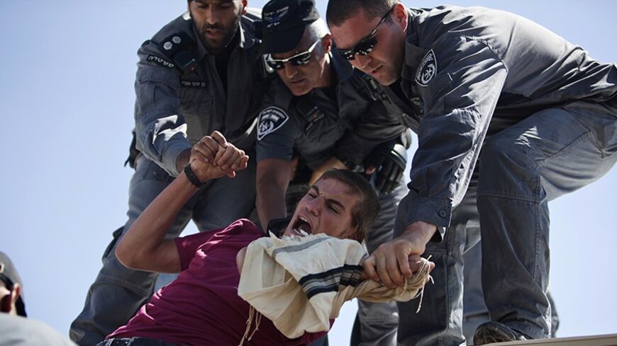 Israeli police scuffle with a Jewish settler as they remove him from a roof on which he barricaded himself in the illegal outpost of Migron, near the West Bank city of Ramallah, after eviction orders were handed to the residents September 2, 2012. Jewish settler families were removed from the unauthorised outpost in the occupied West Bank on Sunday, police said, after they fulfilled an Israeli supreme court order to vacate their homes. REUTERS/Nir Elias (WEST BANK - Tags: POLITICS CIVIL UNREST) - RTR37ECE