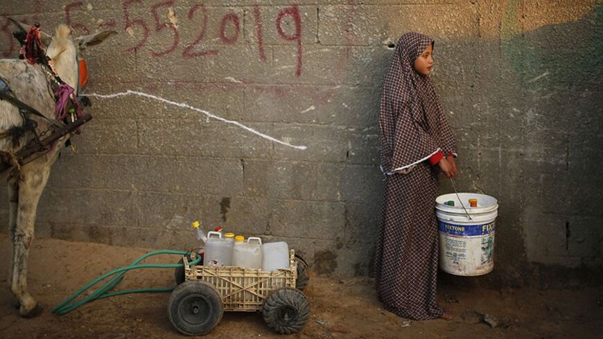 A Palestinian girl waits to fill her containers with water from public taps in Beit Lahiya, near the border between Israel and the northern Gaza Strip, February 25, 2014. REUTERS/Mohammed Salem (GAZA - Tags: SOCIETY TPX IMAGES OF THE DAY) - RTR3FPN6
