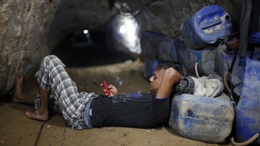 A Palestinian tunnel worker uses his mobile as he rests inside a smuggling tunnel beneath the Gaza-Egypt border in the southern Gaza Strip July 19, 2013. The Islamist group Hamas appealed to Egypt's new rulers on Thursday not to pursue its destruction of smuggling tunnels into the Gaza Strip, warning they risked throttling the small Palestinian territory. REUTERS/Ibraheem Abu Mustafa (GAZA - Tags: POLITICS TPX IMAGES OF THE DAY) - RTX11ROK