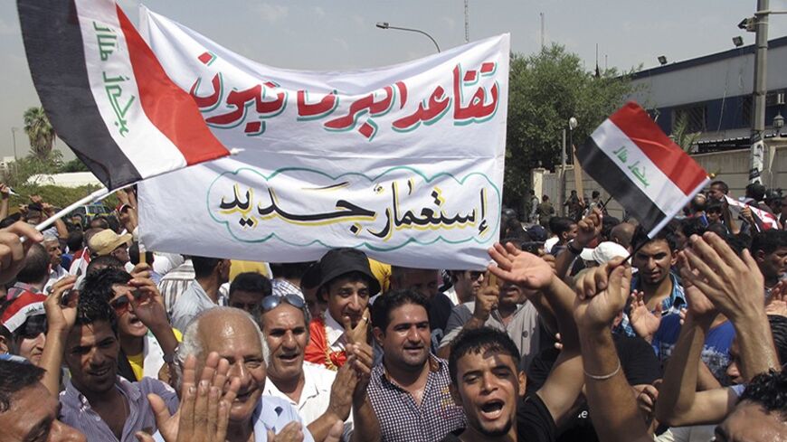 Protesters hold a banner that reads "Retired parliamentarians neo-colonialism" during a demonstration demanding that the pensions of parliamentarians be cancelled in Baghdad, August 31, 2013. REUTERS/Thaier al-Sudani (IRAQ - Tags - Tags: POLITICS BUSINESS EMPLOYMENT SOCIETY CIVIL UNREST) - RTX132E5