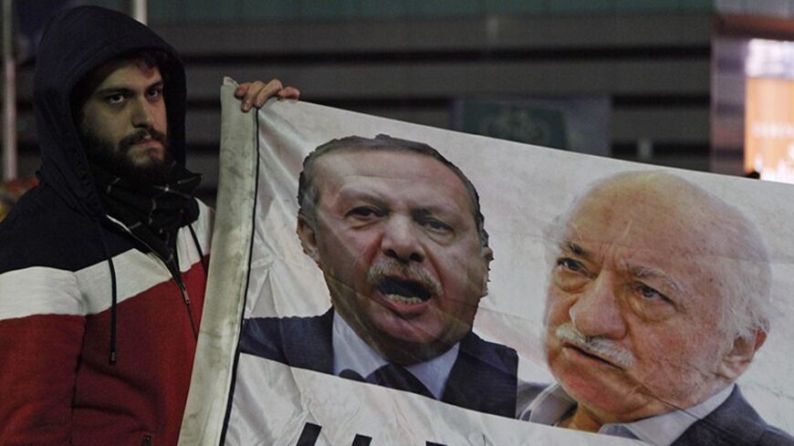 A demonstrator hold pictures of Turkey's Prime Minister Tayyip Erdogan and Turkish cleric Fethullah Gulen (R), during a protest against Turkey's ruling AK Party (AKP), demanding the resignation of Erdogan, in Istanbul December 30, 2013. Erdogan swore on Sunday he would survive a corruption crisis circling his cabinet, saying those seeking his overthrow would fail just like mass anti-government protests last summer. Gulen denies involvement in stirring up the graft case, but he regularly censures Erdogan, a 