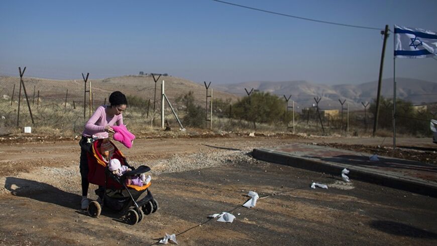 A Jewish settler with a baby in a stroller attends a dedication ceremony for a new neighbourhood in the Jewish settlement of Gitit in the Jordan Valley January 2, 2014. Control of the Jordan Valley is one of a number of contentious issues causing disputes during the current Israeli-Palestinian peace talks. U.S. Secretary of State John Kerry arrived in Israel on Thursday to help re-energise the peace negotiations. REUTERS/Ronen Zvulun (WEST BANK - Tags: POLITICS REAL ESTATE SOCIETY) - RTX16ZU3