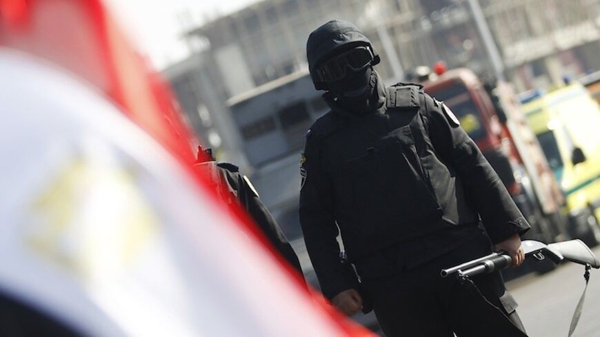 A member of the security forces stands guard near a national flag outside a police academy, where the trial of ousted Egyptian President Mohamed Mursi and members of the Muslim Brotherhood is due to take place, on the outskirts of Cairo, January 28, 2014. Mursi went on trial at a Cairo police academy on Tuesday on charges in connection with a mass jail break during the 2011 uprising, state television reported. REUTERS/Amr Abdallah Dalsh  (EGYPT - Tags: POLITICS CRIME LAW CIVIL UNREST) - RTX17Y5A