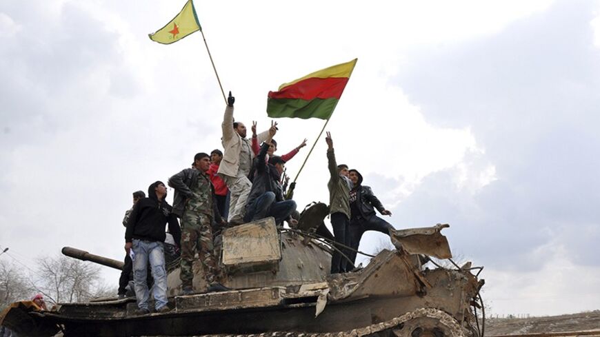 Civilians and members of the Kurdish People's Protection Units (YPG) gesture and raise flags atop a tank that belonged to fighters from the al Qaeda-affiliated Islamic State of Iraq and the Levant (ISIL), in al-Manajeer village of Ras al-Ain countryside January 28, 2014. REUTERS/Rodi Said (SYRIA - Tags: POLITICS CIVIL UNREST CONFLICT) - RTX17YNR
