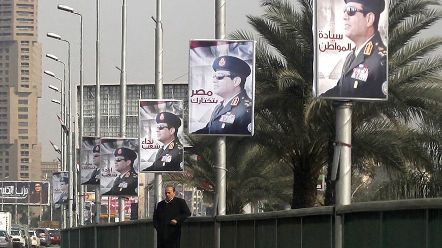 A man stands on a bridge where huge posters of Egypt's Army chief Field Marshal Abdel Fattah al-Sisi are hanged in central Cairo February 3, 2014. Egypt is pushing ahead with an army-backed plan for political transition, with presidential and parliamentary elections due to take place within months. Sisi is widely expected to announce his presidential bid and win easily.   REUTERS/Asmaa Waguih  (EGYPT - Tags: POLITICS) - RTX186DU