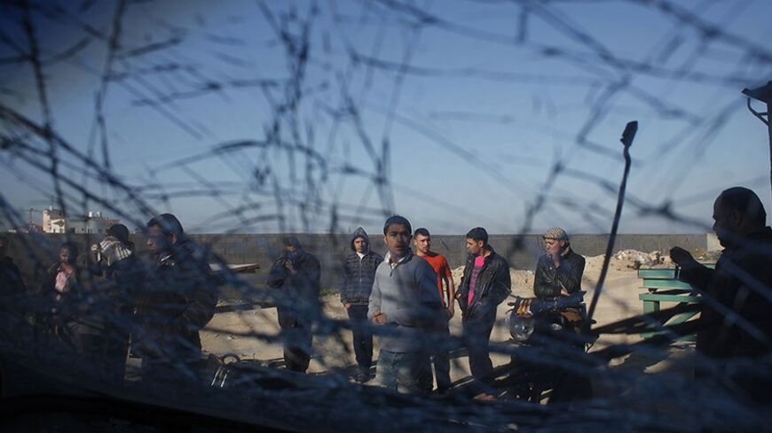 Palestinians are seen through a damaged car window as they look at the scene of an Israeli air strike in the centre of the Gaza Strip February 9, 2014. An Israeli air strike on the Gaza Strip on Sunday critically wounded a Palestinian whom the military said was responsible for launching rockets at southern Israel. REUTERS/Ibraheem Abu Mustafa (GAZA - Tags: POLITICS CIVIL UNREST TPX IMAGES OF THE DAY) - RTX18GBQ