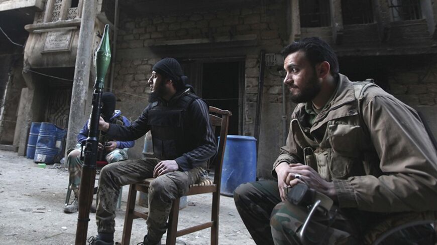 Free Syrian Army fighters sit as a fellow fighter holds an RPG along a street in Deir al-Zor, eastern Syria February 19, 2014. Picture taken February 19, 2014. REUTERS/Khalil Ashawi (SYRIA - Tags: POLITICS CIVIL UNREST) CONFLICT) - RTX1964P