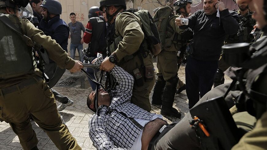 Israeli soldiers carry a Palestinian protester as they detain him during clashes at a demonstration against the closure of Shuhada street to Palestinians, in the West Bank city of Hebron February 21, 2014. Hundreds of protesters, including foreign activists, gathered on Friday to mark the 20th anniversary of the closure of the street, which was closed by the Israeli army in 1994. The closure was after the Hebron mosque massacre by Baruch Goldstein, an Israeli settler, who went on a rampage inside Al Ibrahim