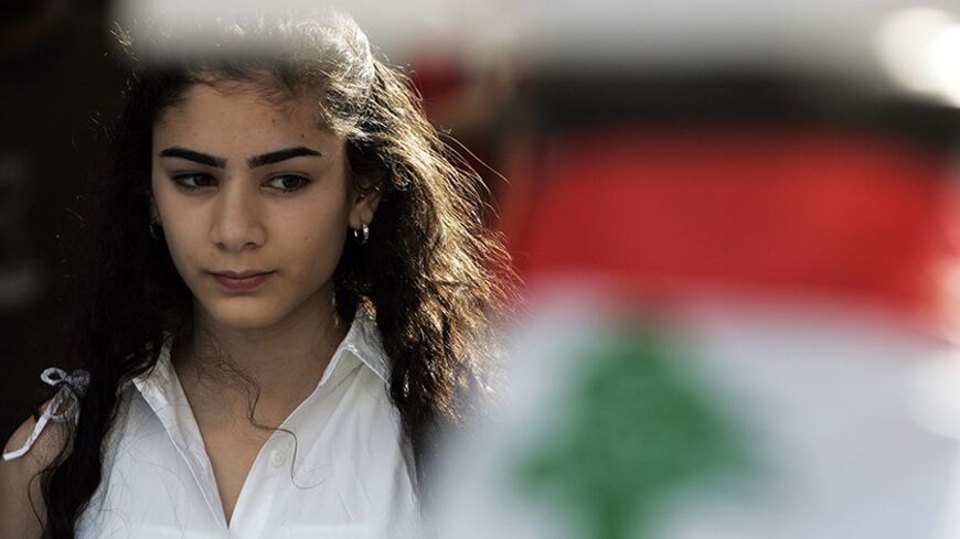 A Lebanese girl is seen behind a national flag as she attends a protest against killings during recent clashes in central Beirut May 18, 2008. Rival Lebanese leaders made progress towards ending their political crisis on Sunday but disagreements over Hezbollah's weapons remained a major hurdle to a Qatari-mediated deal.     REUTERS/Damir Sagolj   (LEBANON) - RTX5VJ7