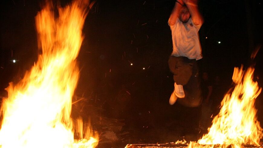 An Iranian man jumps over a fire to mark the last Tuesday of the Iranian calendar year in Tehran, Iran March 14, 2006. REUTERS/Morteza Nikoubazl - RTR175XZ