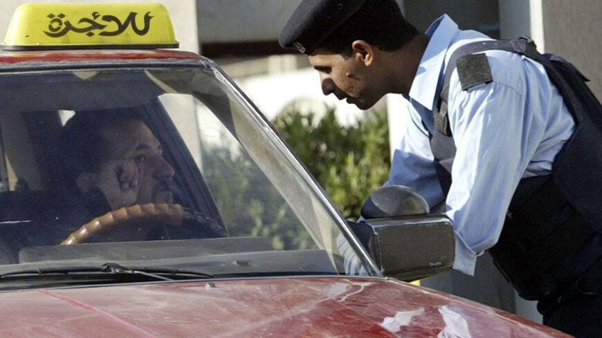 A police officer talks to a taxi driver at a checkpoint during a curfew in Baghdad November 24, 2006. Baghdad was under curfew on Friday and the government appealed for calm after car bombs in a Shi'ite stronghold killed 202 in the bloodiest single attack of the war, pushing Iraq closer to the abyss of anarchy.           REUTERS/Mohammed Ameen          (IRAQ) - RTR1JNM5